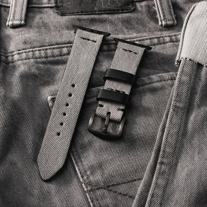 Roarstraps Apple Watch kot saat kayışı, gri denim kumaşın üzerinde şık bir görünüm sunuyor