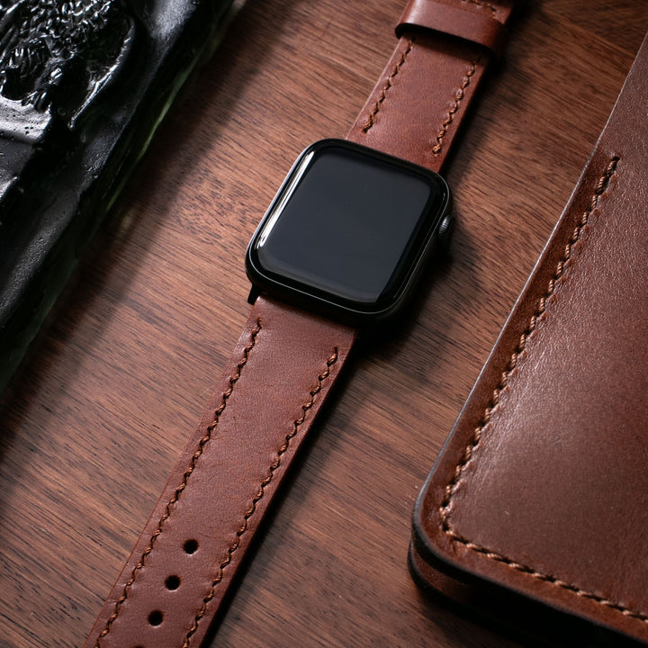 Roarstraps el yapımı deri Apple Watch kayışı, şık tasarımıyla ahşap yüzeyde.