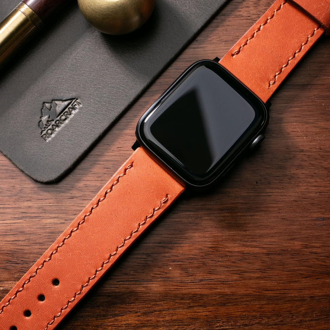 Roarstraps el yapımı deri saat kayışı ile birlikte akıllı saat ve ahşap masa üzerinde görüldü