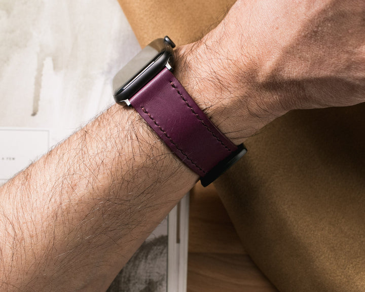 Kahverengi arka planda kol üzerinde el yapımı deri Apple Watch kayışı