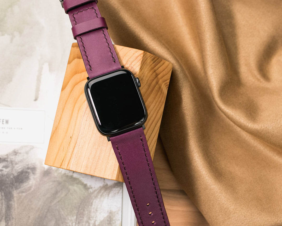 El yapımı deri Apple Watch kayışı, mor renkte ve zarif dikiş detaylarıyla şık bir görünüm sunuyor.